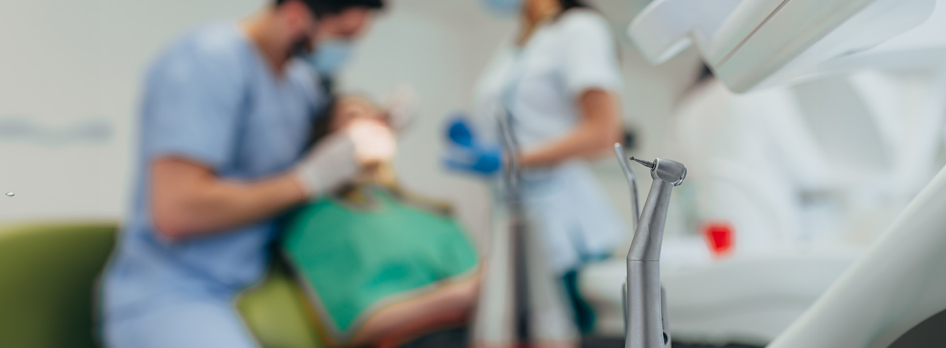 Medical professionals attending to a patient in a dental chair during a dental procedure.