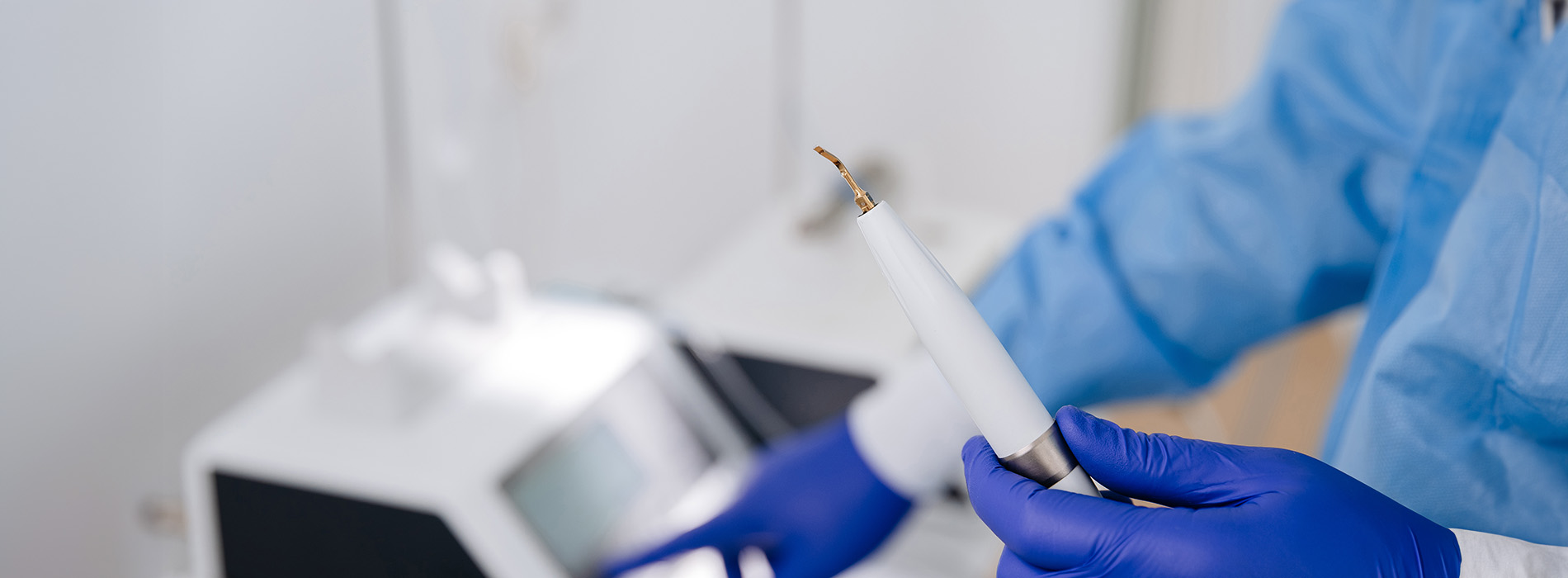 A person wearing protective gloves and a face mask holds a small device over a white substance.