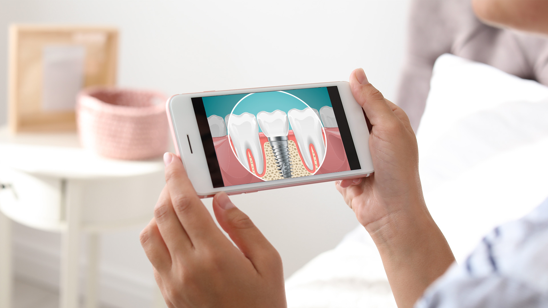 The image shows a person holding a smartphone displaying an animated diagram of a tooth with a cavity being filled, while another tooth has a denture inserted.