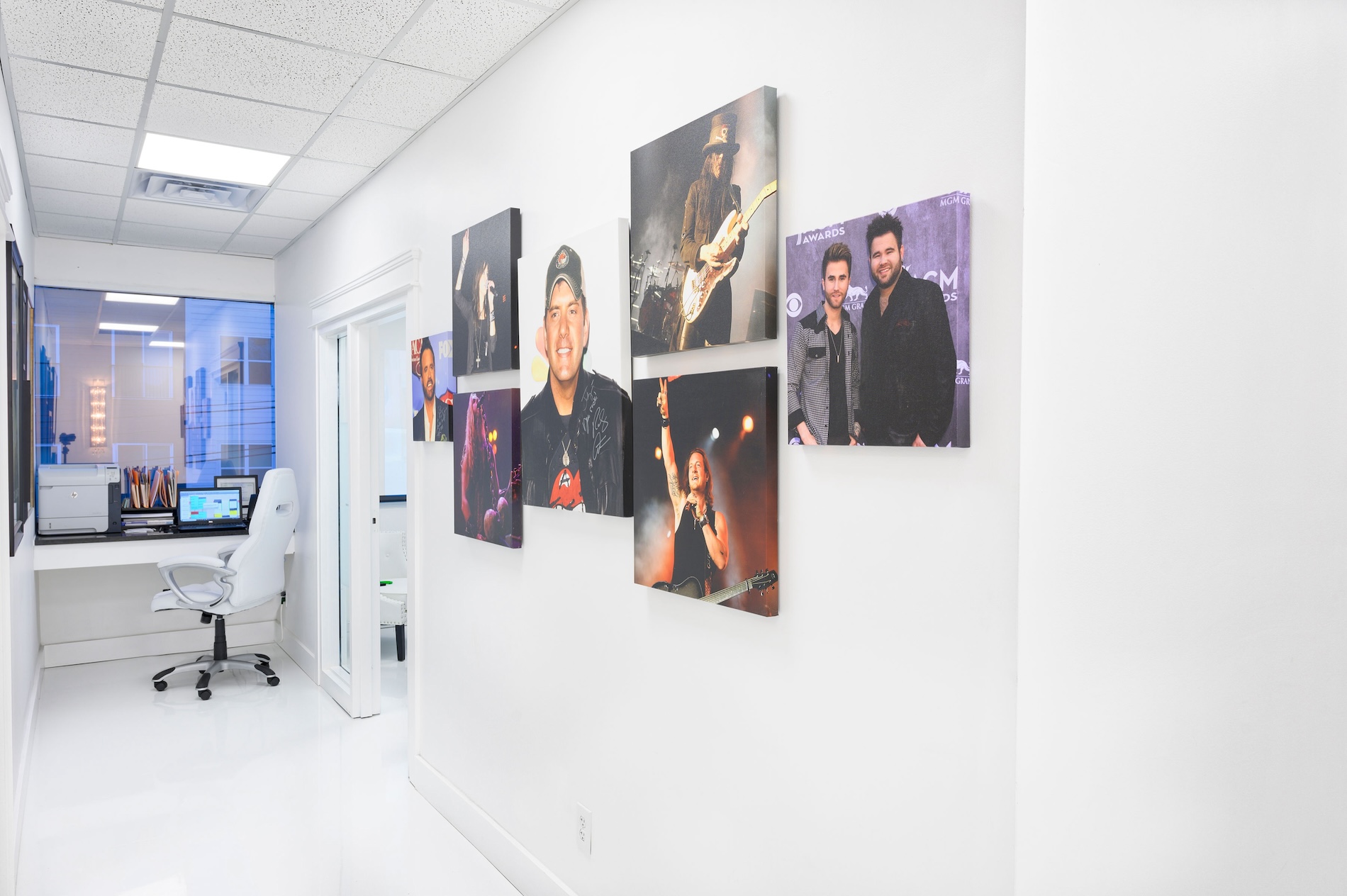 The image shows a wall in an office with multiple framed photographs displayed on it.