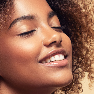 The image shows a close-up of a person with their eyes closed, smiling softly, and appears to be enjoying a moment of relaxation or contentment.