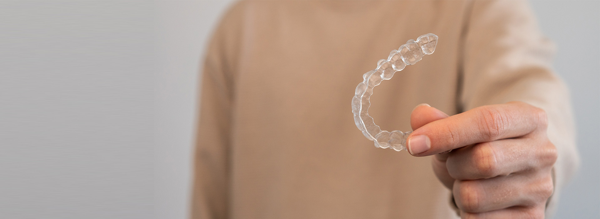 The image shows a person holding a soap bubble between their fingers with a blurred background.