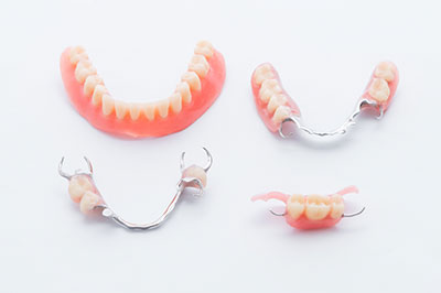 The image displays three sets of dentures with visible teeth, placed side by side against a white background.
