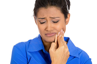 A woman with her eyes closed, holding her nose while looking upwards.