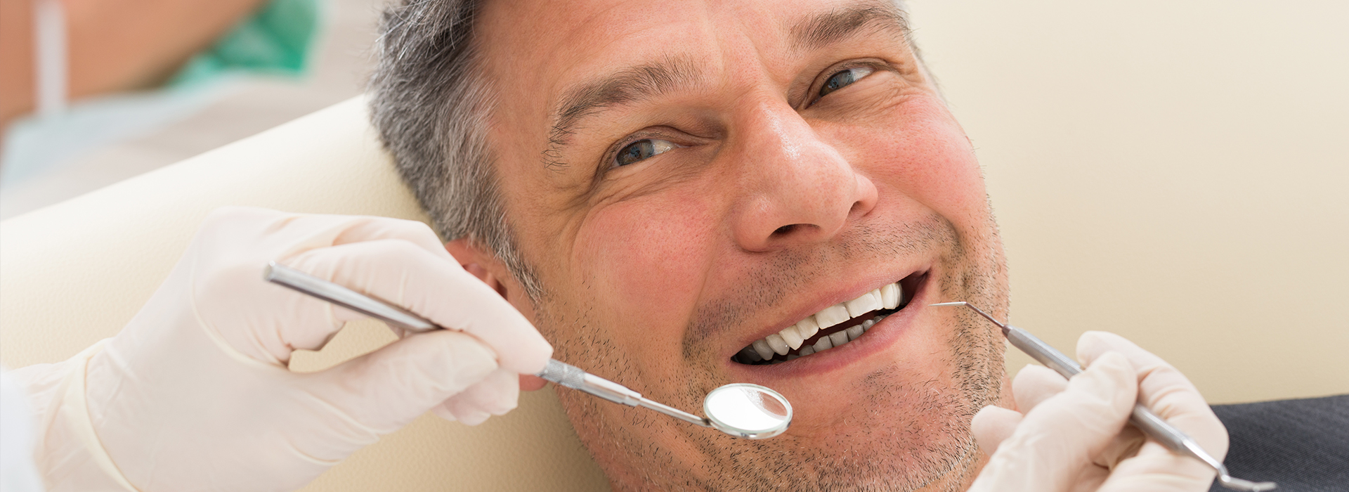 A man receiving dental treatment from a dentist, with dental tools visible.