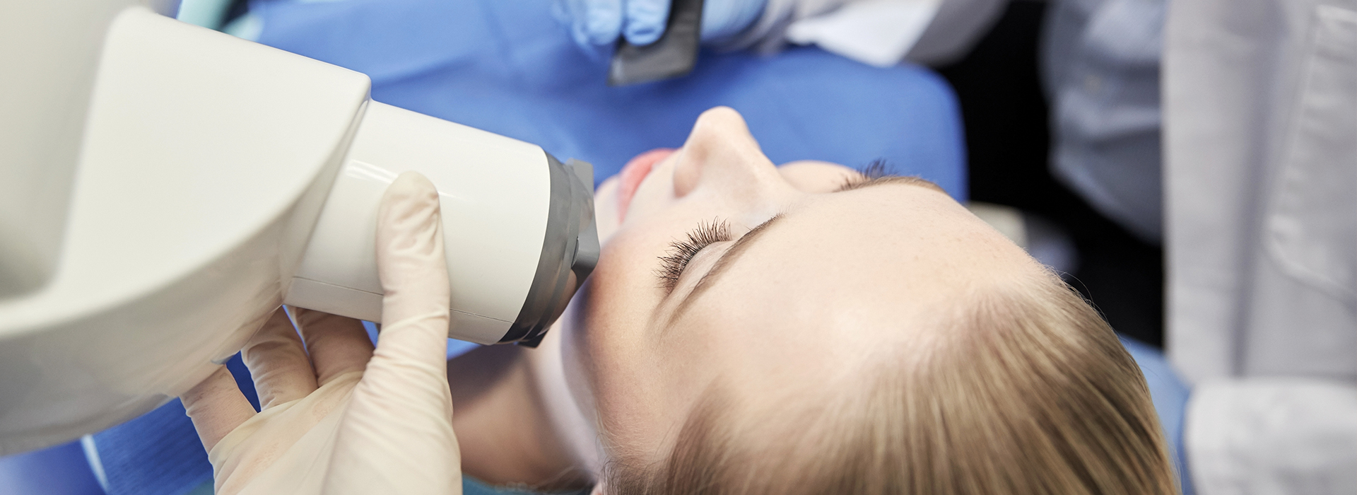 A woman receiving dental treatment while seated in a dentist s chair with a dental professional performing the procedure.