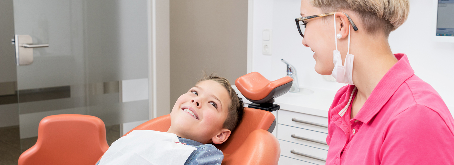 A young boy receiving dental care from a woman in an office setting.