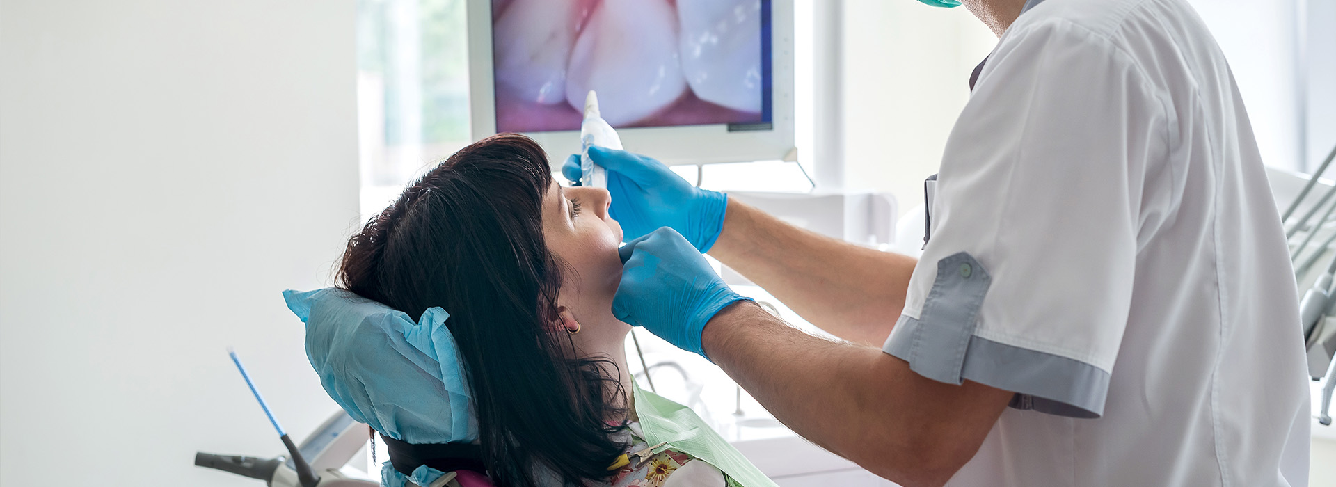 A dentist performing dental work on a patient s mouth while wearing protective gear.
