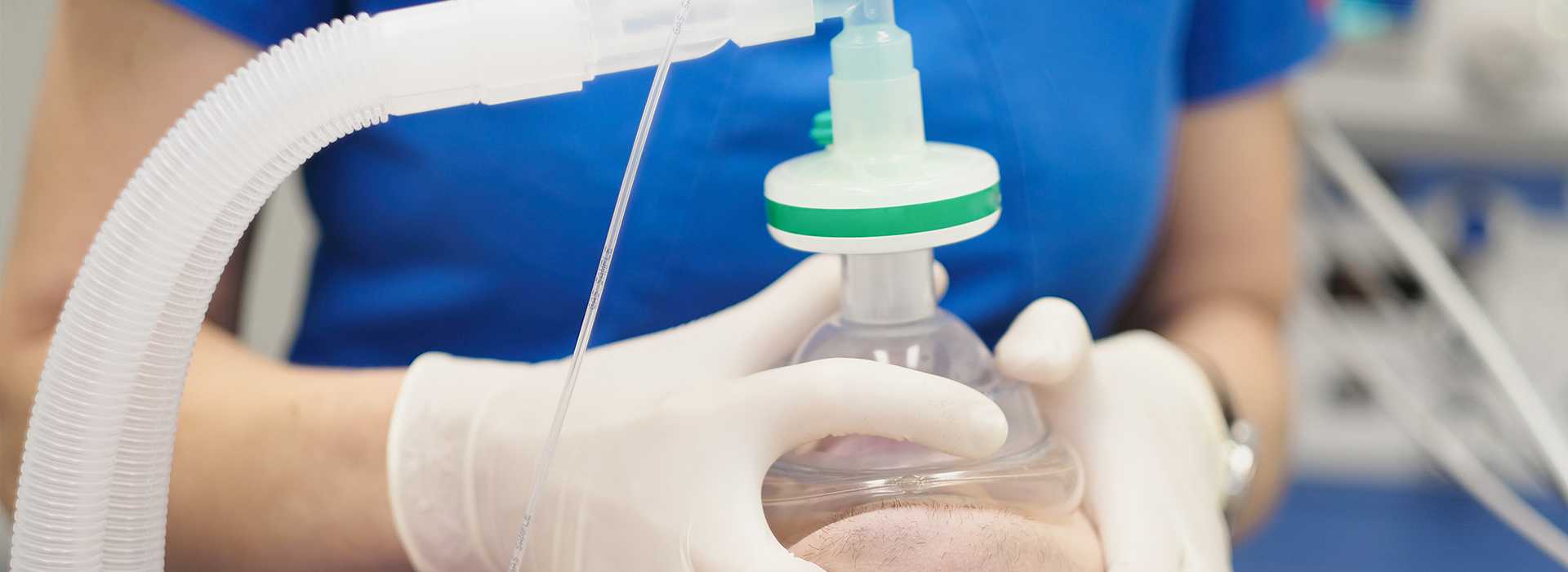Woman wearing gloves holding a medical device with clear tubing and green top.