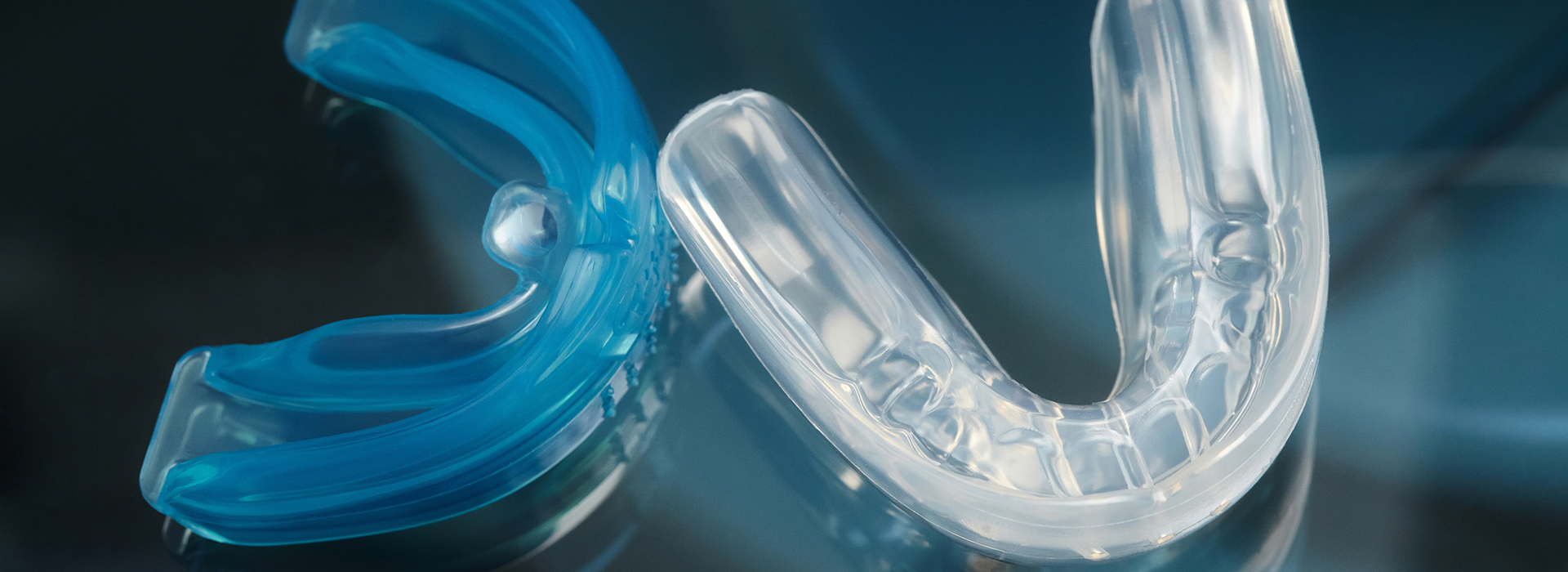Clear plastic dental retainer with a blue toothbrush partially visible.