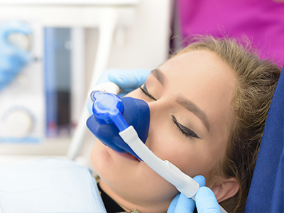 A woman receiving medical treatment with an oxygen mask on her face while lying on a hospital bed.